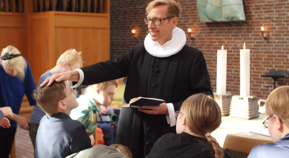 En præst konfirmerer konfirmander med særlige behov.