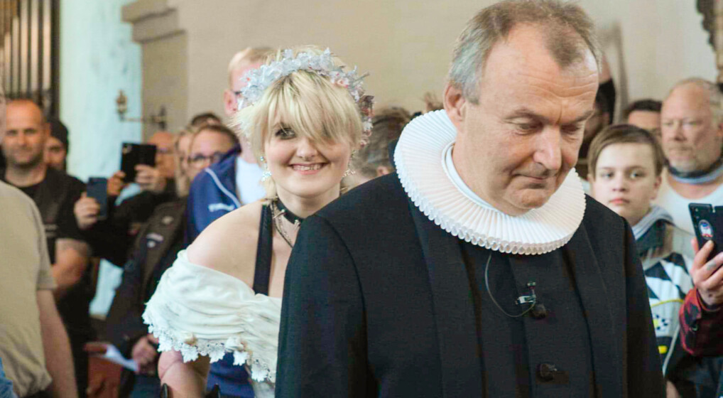 Rina Bjerring Pedersen er på vej ind i kirken sammen med præsten Jakob Hjørnholm til toner fra 'The Walking Dead'. Hun bærer en konfirmationskjole med laser og teaterblod.