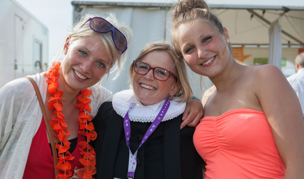 Præst og to unge kvinder holder om hinanden på festival