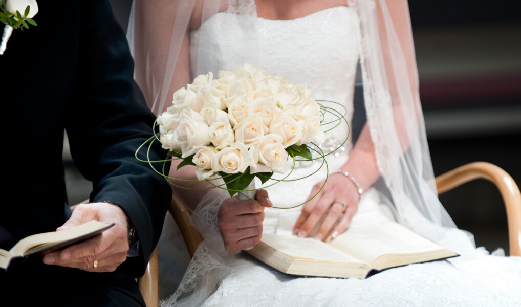 Brudepar sidder ved siden af hinanden ved bryllup i folkekirken