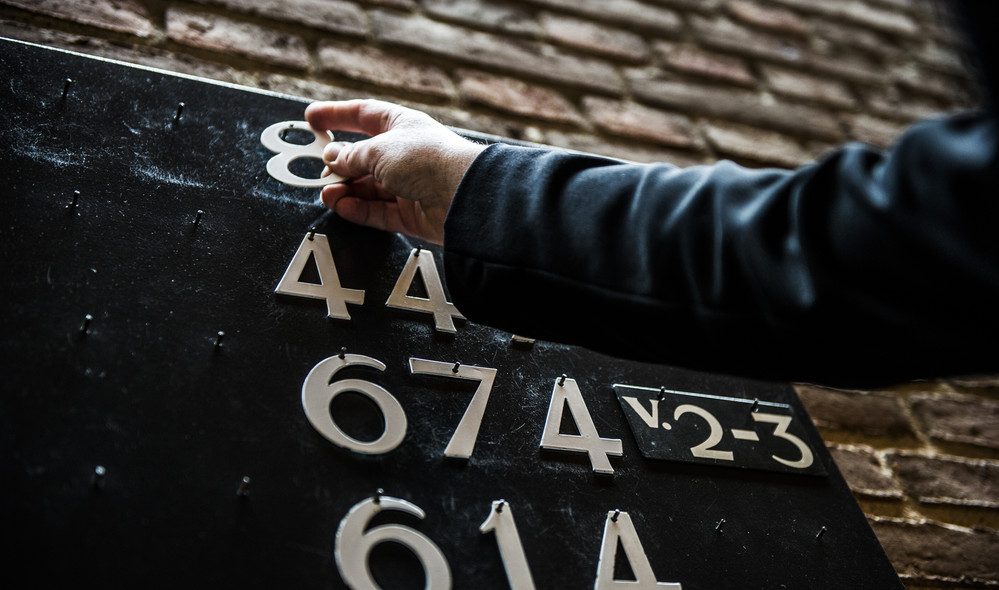 Kirketjener sætter salmenumre op på tavle i kirken før gudstjeneste